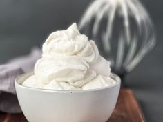 a white bowl filled with whipped cream on top of a wooden table