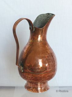 a copper colored pitcher sitting on top of a table