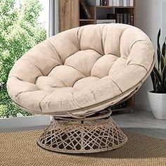 a round chair sitting on top of a rug next to a potted plant in front of a window