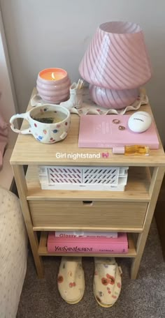 a night stand with books, cups and candles on it