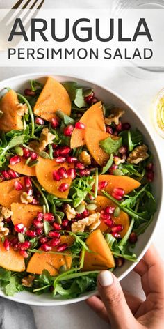 a white bowl filled with spinach and pomegranate on top of a table