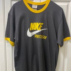 New With Tags Size Large (Seems More Similar To An Xl) Gray T-Shirt With Yellow Trim Design In Collar And Sleeves Vintage Design Single Stitched Gray Athleisure Tops For Sports Season, Sporty Gray Top For Streetwear, Nike Gray Tops With Letter Print, Nike Varsity Tops For Sports Season, Gray Sportswear Top For Streetwear, Gray Crew Neck Athleisure Tops, Gray Short Sleeve Tops For Sports Season, Nike Sportswear Tops With Letter Print, Gray Logo Print Top For Sports Season