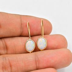 Natural Australian Opal Earrings (Pair) ✪Gemstone: Natural Australian Opal  ✪Metal: 18k solid Yellow gold. ✪Stone size: 6x8 mm. ✪Stone Shape :Oval  ✪Stone Weight : 2 Ct. ✪ Earring Weight : 1.25 Gram ✪Earring Length : 25 mm. ✪Earring width : 7 mm. ✪Setting type: Bezel wire setting. If you need any other preferred stone please contact us. Opal benefits - *The stone is believed to counteract bad effects and bring prosperity, beauty, love, and romance in like.  *It brings success in dating and benefits those who are in dairy and hospitality industry. *Opal gemstone benefits include enhancing joy in marital life.   QUALITY OF MATERIALS: Metal: Most of our jewelry at JewelryMansion is made with precious metals like gold and silver. These metals are 100% non-allergic to our skin. Gemstone: All of Fine Jewelry Opal Earrings For Gift, Opal Yellow Gold Earrings For Gifts, Yellow Gold Opal Earrings Gift, Yellow Gold Opal Gemstone Earrings, Yellow Gold Opal Earrings For Gifts, Gold Opal Cabochon Earrings, Oval Opal Earrings In Yellow Gold, Yellow Gold Oval Opal Earrings, Elegant Ethiopian Opal Earrings As Gift