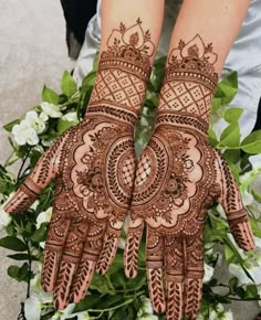 two hands that are decorated with henna and some flowers in front of them on the ground