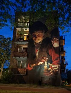 a large painting on the side of a building with two people holding a lit candle