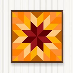 an orange and red star quilt hanging on a wall next to a white striped wall