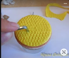 a person is using a plastic tool to decorate a cupcake with yellow icing