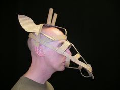 a man wearing a paper mask with sticks attached to it's head and eyes