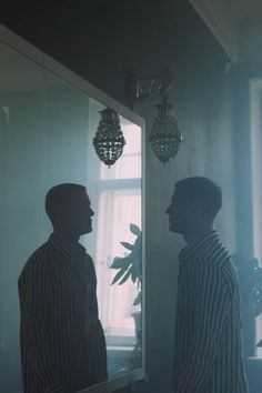 a man standing in front of a mirror next to a plant