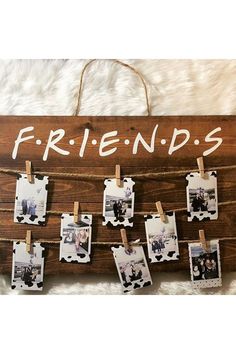 a wooden sign that says friends hanging on clothes pegs with pictures pinned to it