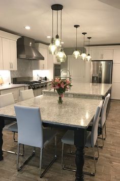 a large kitchen with an island in the middle and lots of white chairs around it