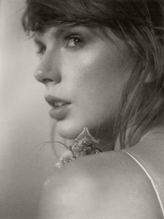 a black and white photo of a woman's neck with flowers in her hair