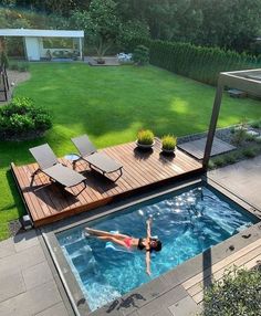 a woman swimming in a small pool surrounded by grass