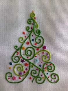 a small christmas tree made out of colored beads on a white fabric background with green and red swirls