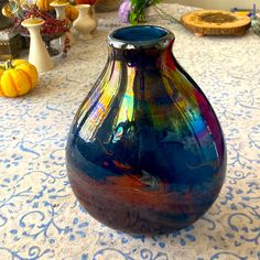 a blue vase sitting on top of a table next to pumpkins and other decorations