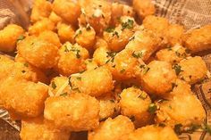 some fried food sitting on top of a wooden plate with parsley sprinkled on it