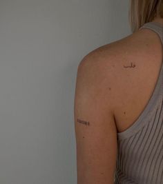 the back of a woman's shoulder with an arabic script tattoo on her left arm