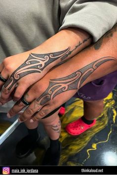 two people with tattoos on their arms and hands, one holding the other's hand