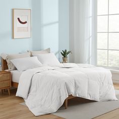 a bed with white linens and pillows in a room next to a large window