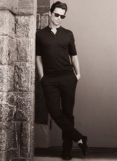 a man standing on the steps in front of a building wearing sunglasses and a black shirt