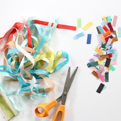 scissors and colored streamers on a white surface next to each other with one pair of scissors in the foreground