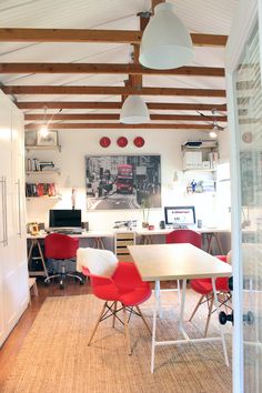 an office with red chairs and a white table in the middle of the room,