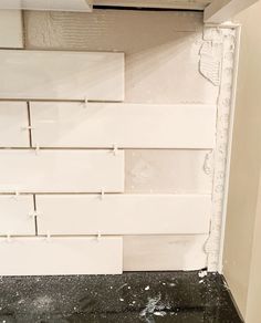 a wall with white tiles in the middle and black flooring on it's side