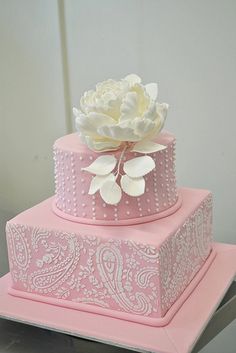 a three tiered pink cake with white flowers on top