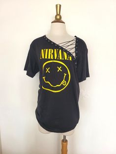 "Nirvana Lace Up Band Top T Shirt - Grunge - Smiley Face Nevermind Each piece is uniquely designed and one of its' kind. Hand stitched edge detailing for superior quality and unique finish. Please note, since this is a handmade item, there may be slight variances with each T.  UNISEX Sizing (women may choose to size down depending on fit preference) Appx. Measurements Laying Flat: S: 17\" across chest Width x 28\" Length M: 19\" across chest Width x 29\" Length L: 21\" across chest Width x 31\" Length ** If you have a custom idea or would like to mix and match a design idea seen in my shop, feel free to contact me anytime **" Edgy Festival T-shirt With Crew Neck, Vintage Distressed T-shirt For Festivals, Edgy Acid Wash T-shirt For Alternative Fashion, Grunge Festival Top With Screen Print, Grunge Screen Print Top For Festival, Distressed Graphic Tee For Festival, Distressed Graphic Tee For Festivals, Festival Grunge Style Top With Screen Print, Vintage Distressed Tops For Music Festival