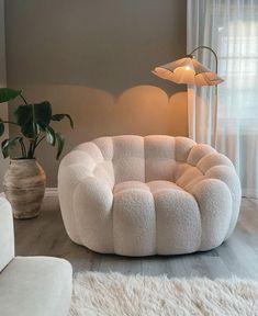 a living room with white furniture and a large potted plant in the corner on the floor