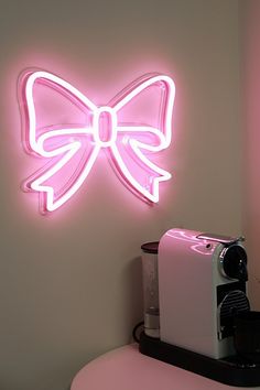 a pink bow neon sign mounted to the side of a wall next to a toaster