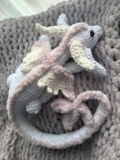 a crocheted blanket with two stuffed animals on it's side, laying down