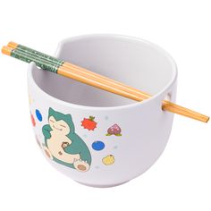 two chopsticks sticking out of a bowl with an image of a cat and fish on it