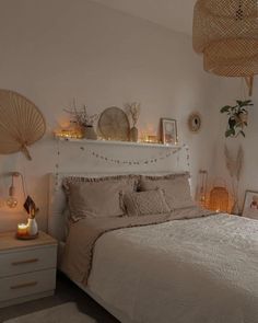 a white bed sitting next to a night stand with lights on it's headboard