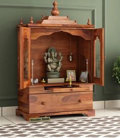 a wooden cabinet with an elephant statue on top and other items in the bottom drawer