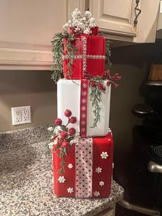 three wrapped presents stacked on top of each other in front of a kitchen countertop