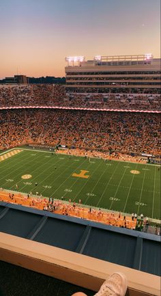 a football stadium filled with lots of people sitting on the bleachers at sunset