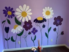 the wall is painted with flowers and paintbrushes in front of it, along with other items