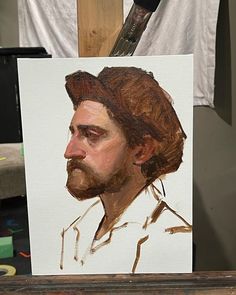 a painting of a man with a beard is being displayed in front of a easel