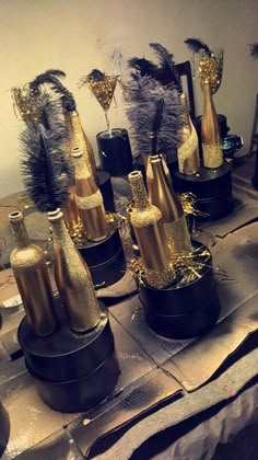 there are many wine bottles that have been decorated with gold and silver feathers on the table