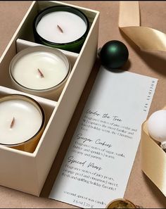 three candles are in a box next to a note and an egg on the table