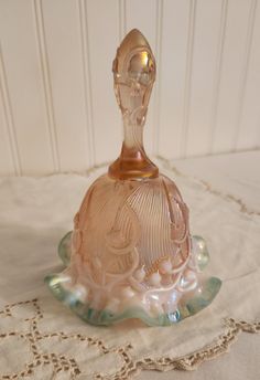 a pink glass perfume bottle sitting on top of a white tablecloth covered table cloth