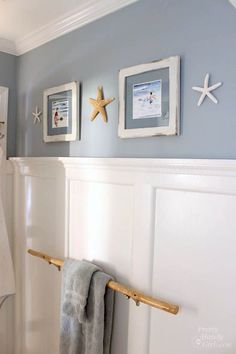 a bathroom with blue walls and pictures on the wall above the toilet, along with a towel rack