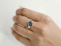 a woman's hand wearing a gold ring with a blue stone