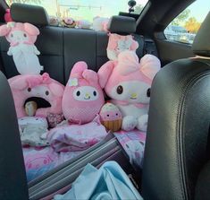 hello kitty stuffed animals in the back seat of a car with pink blankets and pillows