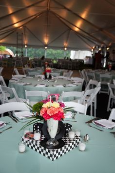 a vase with flowers on top of a table in a tented area for people to dine