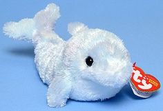 a white stuffed animal laying on top of a blue surface with a tag in it's mouth