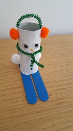 a toilet paper roll snowman sitting on top of a wooden table