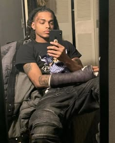 a young man sitting in front of a mirror looking at his cell phone while wearing an arm cast