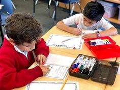 two young boys sitting at desks doing homework